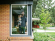 © Jessica Peterson/Tetra Images - Father holding his daughter behind window of house