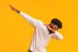 African american guy throwing dab move against orange studio background