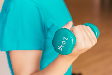 Wall Mural - Stock photo of a young woman holding a dumbbell