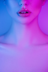 Wall Mural - High Fashion model lips woman in colorful bright neon blue and purple lights, beautiful girl face closeup, trendy glowing make-up, colorful make up. Glitter Vivid neon makeup. Art