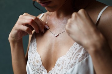 Wall Mural - Girl in a white dress with a  silver chain around her neck. The bride fixes a decoration of a jewel on the neck. Stylish fashionable diamond suspension. girl's neck pendant. pendant for women's neck.