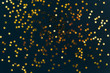 © Ira_Shpiller - Golden star glitter confetti on dark black background. Festive holiday background. Celebration concept.
