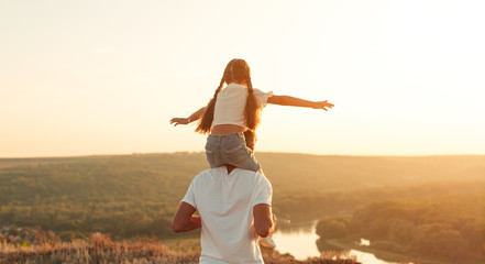 Wall Mural - Carefree father and daughter riding on shoulders along peaceful field