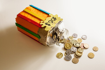 Scattered coins on a white table with a handmade glass piggy bank that says 