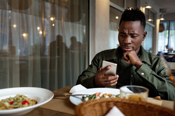 Wall Mural - young african american man messaging online, checking social networks in cafe. copy space