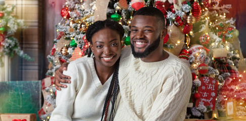 Wall Mural - Black couple enjoying Christmas eve, embracing and smiling at camera