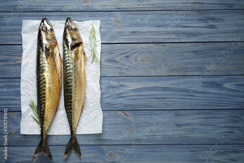 Fotografía Tasty smoked fish on blue wooden table, top view. Space for text