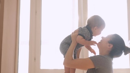 mother and her baby son having fun and playing at home. little kid 1 years old play with his mom arm