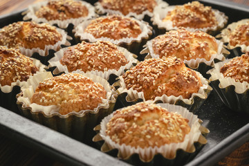 Wall Mural - Baked cupcakes with sesame seeds in aluminum molds on a baking sheet