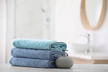 Poster - Stack of fresh towels and soap dispenser on table in bathroom