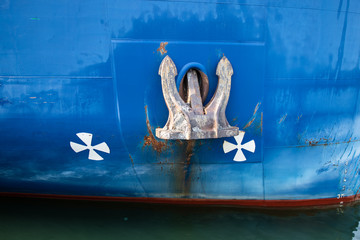 Anchor on blue ship close-up. Rusty anchor on bow of ferryboat or tanker. Detail of marine vessel with big anchor in sea port.