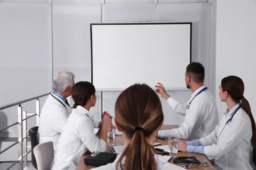 Team of doctors using video projector during conference indoors