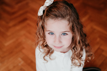 portrait of kid girl decorating christmas tree at home. holding a golden snow flake. Christmas concept