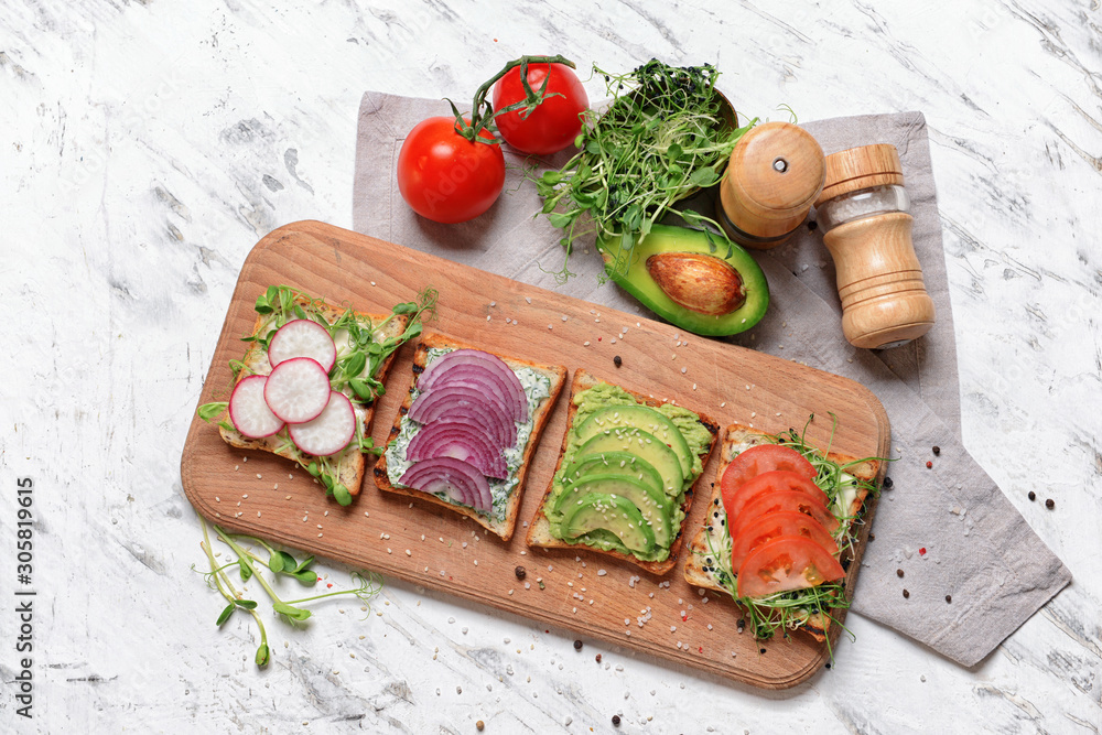 Wooden board with different tasty sandwiches on white background