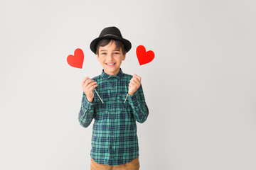 Cute little boy with red hearts on grey background. Valentines Day celebration