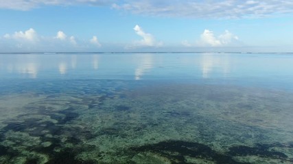 Wall Mural - flying above morning sea over calm tropical waters towards skyline