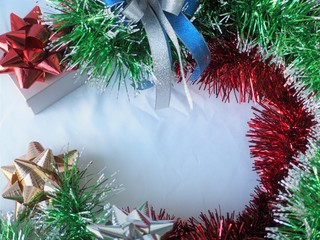 Glossy christmas tinsel decoration and ribbon bows on white background