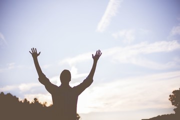 Low angle shot of a person with his hands up praying in nature - concept of faith in God