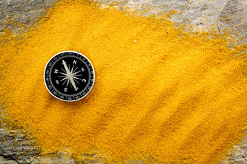 Wall Mural - Travel concept. Compass on yellow sand background top view copy space