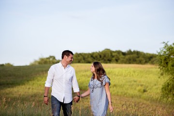 Poster - Beautiful shot  of happy couple holding hands while smiling at each other with blurred background