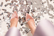 © satura_ - Pair of feet at a new year's eve countdown party with confetti on the floor, top view