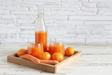 Wall Mural - Fresh carrot and tangerine juice . Healthy vitamins drink in a glass on wooden table background.