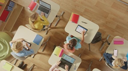 Wall Mural - elementary school computer science classroom: children sitting at their school desk use personal com