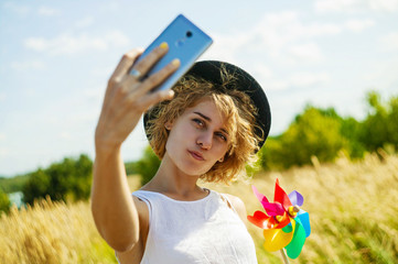 Portrait of a smiling young girl making selfie photo in park.