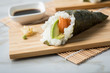 Lachs Fisch Avocado Temaki Sushi, eingelegter Ingwer mit Soja Soße und Sushimatte auf Bambus Brett Teller und Marmor Hintergrund