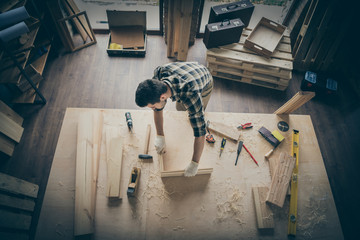 Top above high angle view photo of pensive thougthful craftsman making frame with wooden blocks surrounded with instruments