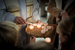 People gathering around Priest lighting candles