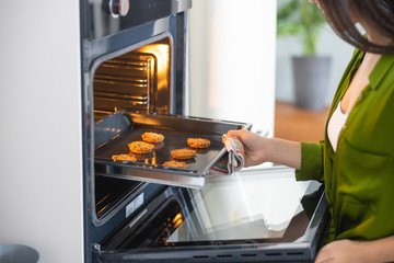 Young Asian housewife opening the convection oven