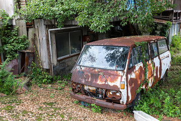 Rusty old car in the yard of an abandoned house.