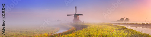 Fotomural Traditional Dutch windmill at sunrise on a foggy morning