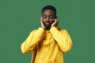 Wall Mural - young black man in yellow hoodie listens to music