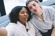 © BullRun - Portrait of positive multicultural young women in casual wear making grimaces and laughing at camera.Happy and joyful caucasian hipster girl resting together with african american friend at home