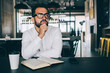 © BullRun - Contemplative male entrepreneur in casual white shirt pondering on startup sitting at table and looking away, Caucasian man in classic spectacles for provide eyes protection creating market strategy