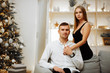 © Skripnik Olga - couple in love kisses and hugs on the sofa near the Christmas tree lights. New year's night. Christmas.