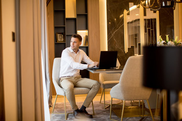 Young man sitting in a luxurious room in front of a laptop computer