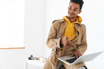 Wall Mural - Photo of african american man using laptop and pointing finger at screen