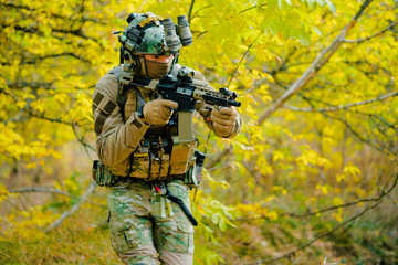 Wall Mural - Airsoft man in uniform, move with machine gun on yellow forest backdrop. Soldier aims at the sight