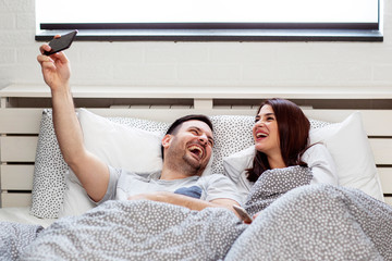 Young couple lying in bed and taking selfie by mobile phone