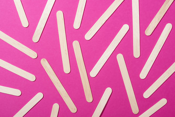 Wall Mural - top view of depilation wooden sticks on pink background