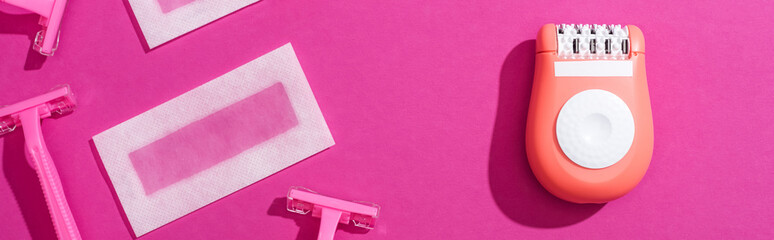 Wall Mural - top view of disposable razors, epilator and wax depilation stripes on pink background, panoramic shot