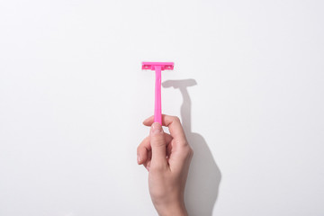 Wall Mural - cropped view of woman holding female pink razor on white background