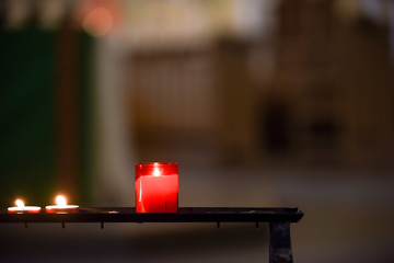 Prayer candles lit inside a church as a votive offering in an act or prayer