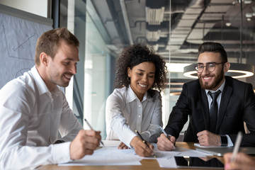 Wall Mural - Smiling diverse businesspeople consider financial paperwork at briefing