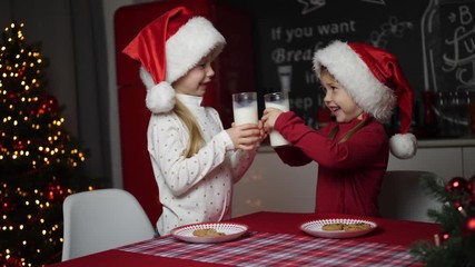 Poster - Cute little children with milk and cookies at table in dining room. Christmas time