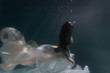 © Underwater girls - Beautiful girl swims underwater with long hair. Blue or gold background like gold. The atmosphere of a fairy tale or magic. Diving under the water with a shiny cloth