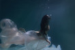 Beautiful girl swims underwater with long hair. Blue or gold background like gold. The atmosphere of a fairy tale or magic. Diving under the water with a shiny cloth